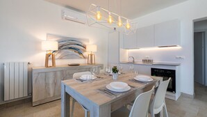 A modern kitchen with a wooden dining table set for four, a built-in stove, and a pendant light fixture.