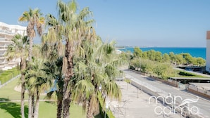 A coastal hotel with palm trees, a clear view of the sea, and a parking area. - Acogedor Apartamento con Piscina a un Minuto de la Playa (Miami Platja)