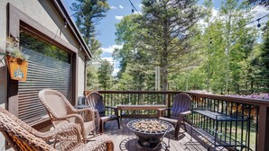 A deck with wicker chairs, a fire pit, and a table. - Home near Monte Verde Lake with forest views (Angel Fire)