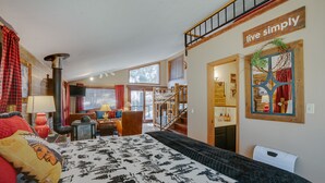 A spacious room with a large bed, a fireplace, a staircase, and a 'live simply' sign. - Home near Monte Verde Lake with forest views (Angel Fire)