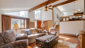 A spacious living room with a large sofa, a leather ottoman, and a patterned rug. - Home near Monte Verde Lake with forest views (Angel Fire)