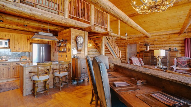 Een vakantiehuisje van hout met een keuken, een eethoek en een trap naar een zolder.
