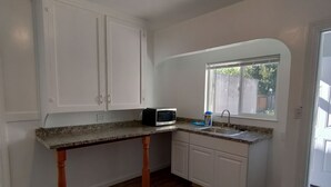 A kitchen with white cabinets, a granite countertop, a microwave, and a window with a view of the outside. - Charming Palo Alto Home Next to Stanford (Palo Alto)