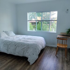 Une chambre à coucher avec un lit, une fenêtre, une chaise et une petite table.