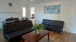 A living room with a dark sofa, a wooden coffee table, and a painting on the wall. - Charming Palo Alto Home Next to Stanford (Palo Alto)