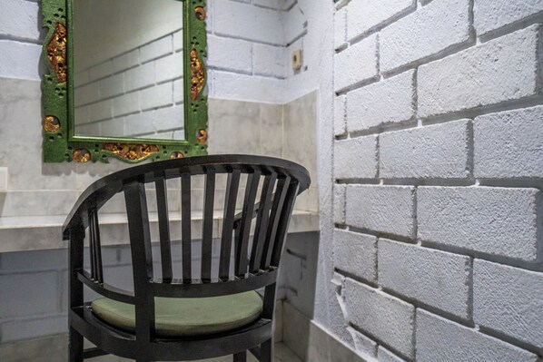 A black chair with a green cushion in a room with white brick walls and a green-framed mirror. - Ammara Legian By Vilarisi - 8 Minute Walk To The Beach (Legian)