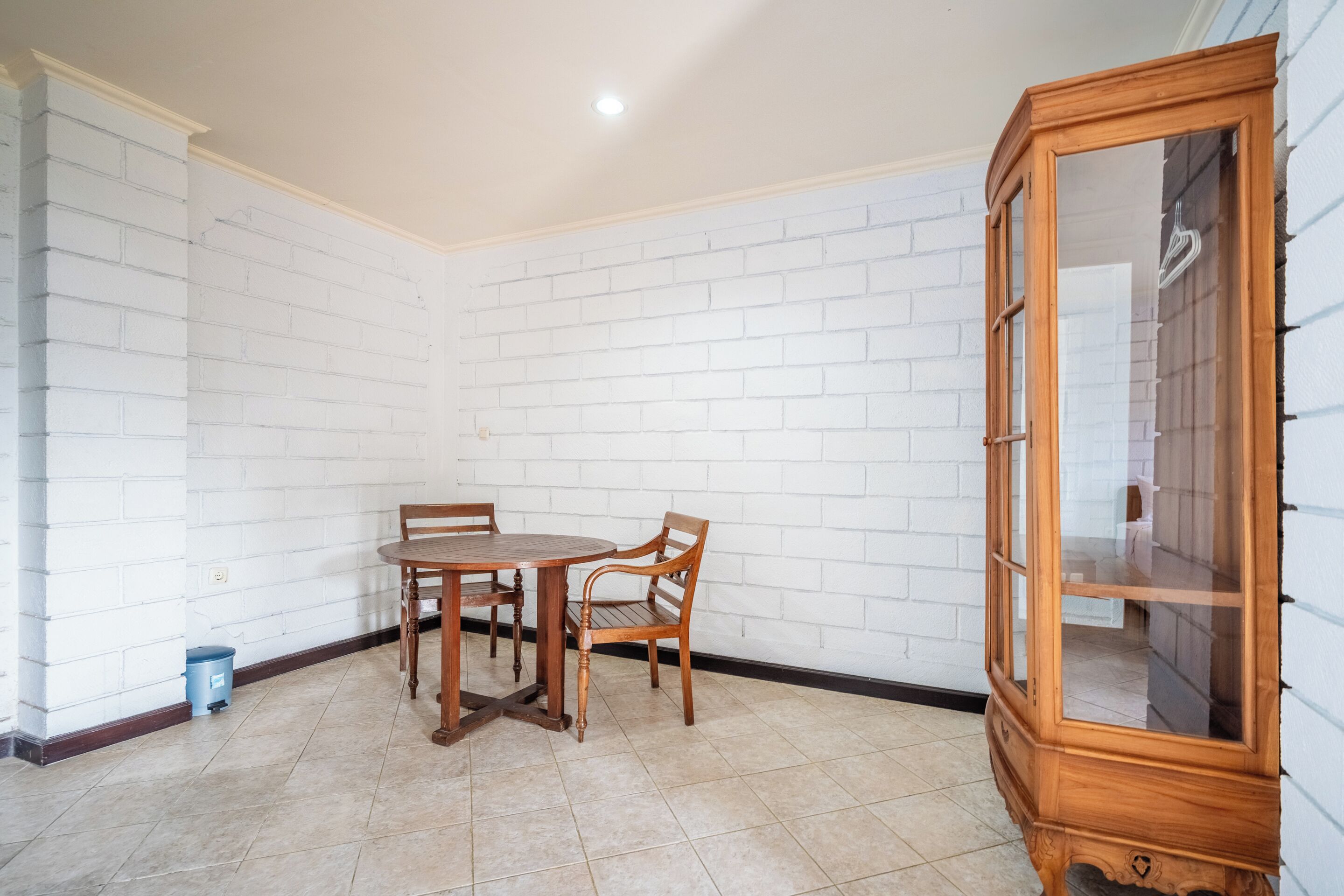 Una habitación con pared de ladrillo blanco, una mesa de comedor de madera con sillas y un mueble de madera.