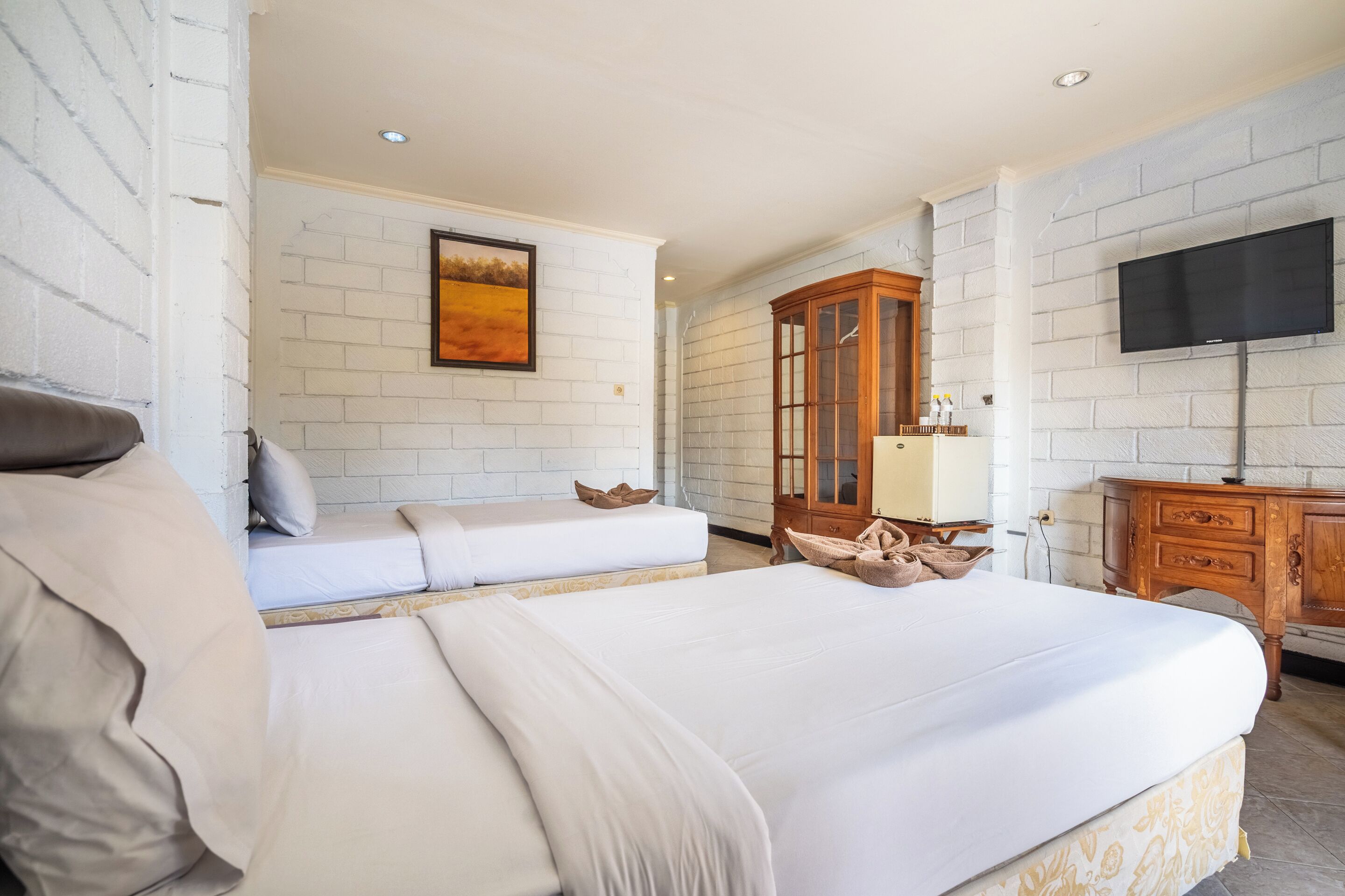 Een hotelkamer met een groot bed, een kleinere zithoek, een houten kast en een flatscreen televisie aan de muur.