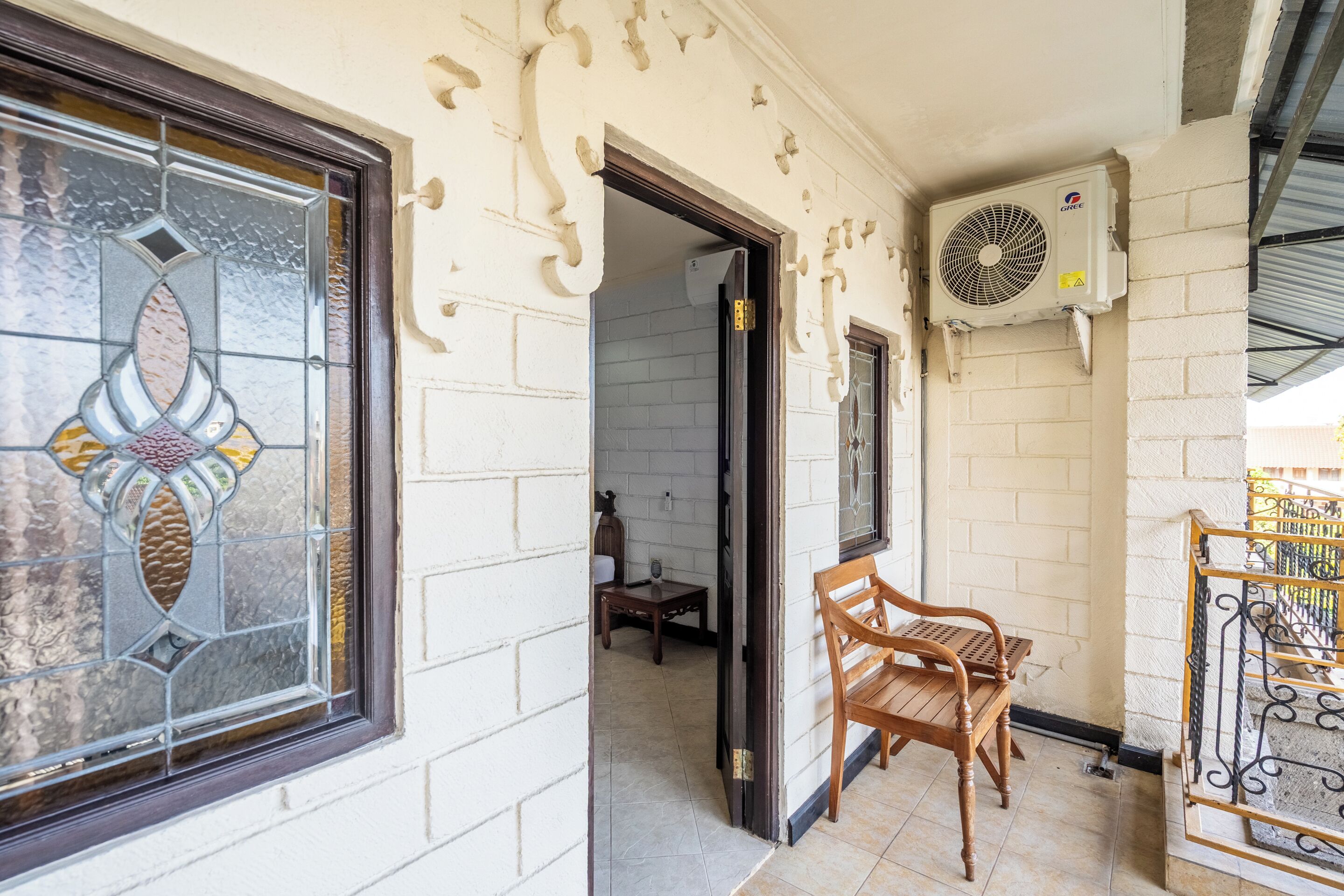 A room with a large window, a wooden chair, a small table, and a wall-mounted air conditioning unit.