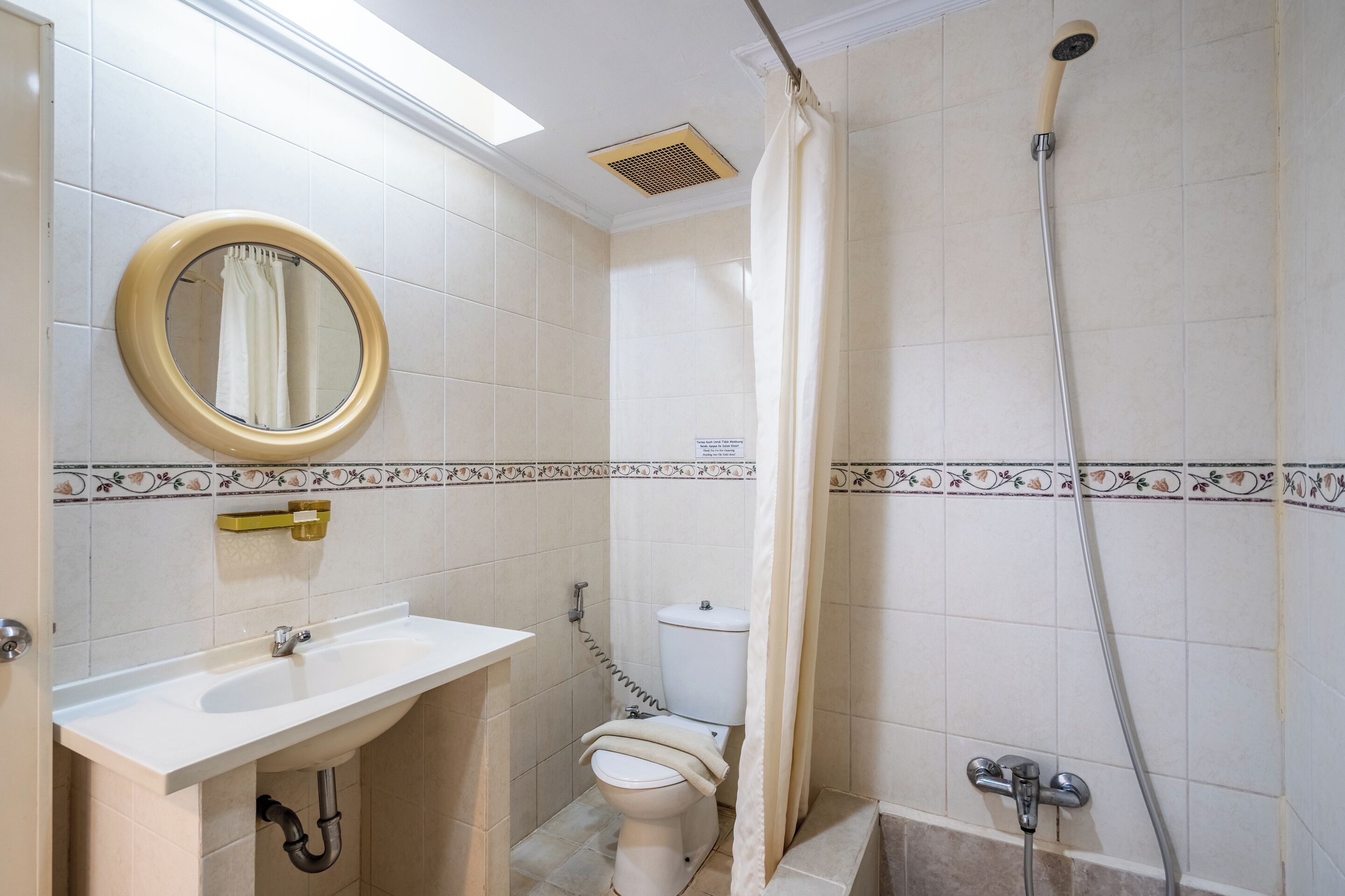 Un baño con inodoro, lavamanos, ducha y espejo.