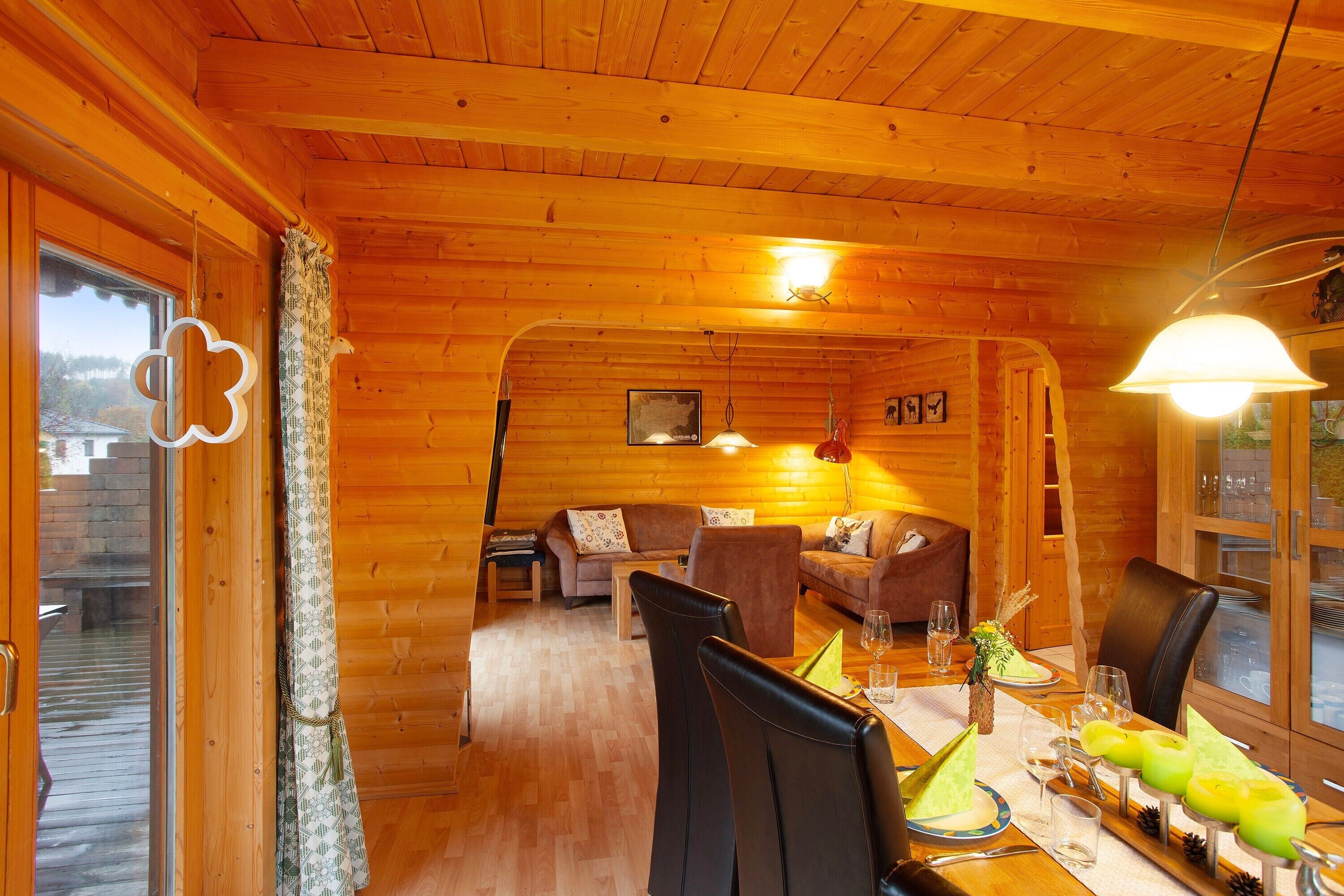 L’intérieur d’un chalet en bois comprend un coin repas, un canapé et une cheminée.