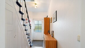 A hallway with a white door, a wooden bench, and a wall-mounted light fixture.