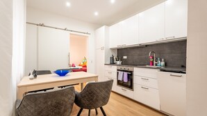 Una cucina moderna con mobili bianchi, un piano di lavoro nero e un'area pranzo con due sedie e un tavolo.