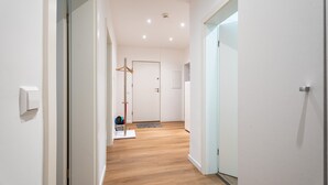 Un corridoio con pavimento in legno, pareti bianche e una porta in fondo.