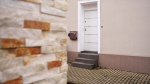 Un ingresso di un edificio con una porta bianca, una cassetta postale e un muro in pietra.