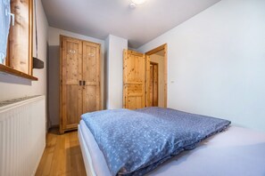 Une chambre à coucher avec un lit, une armoire en bois et une porte donnant sur une autre pièce.