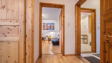 Ein Korridor mit Holzboden, der in einen Wohnbereich mit einer Couch und einem Tisch führt.