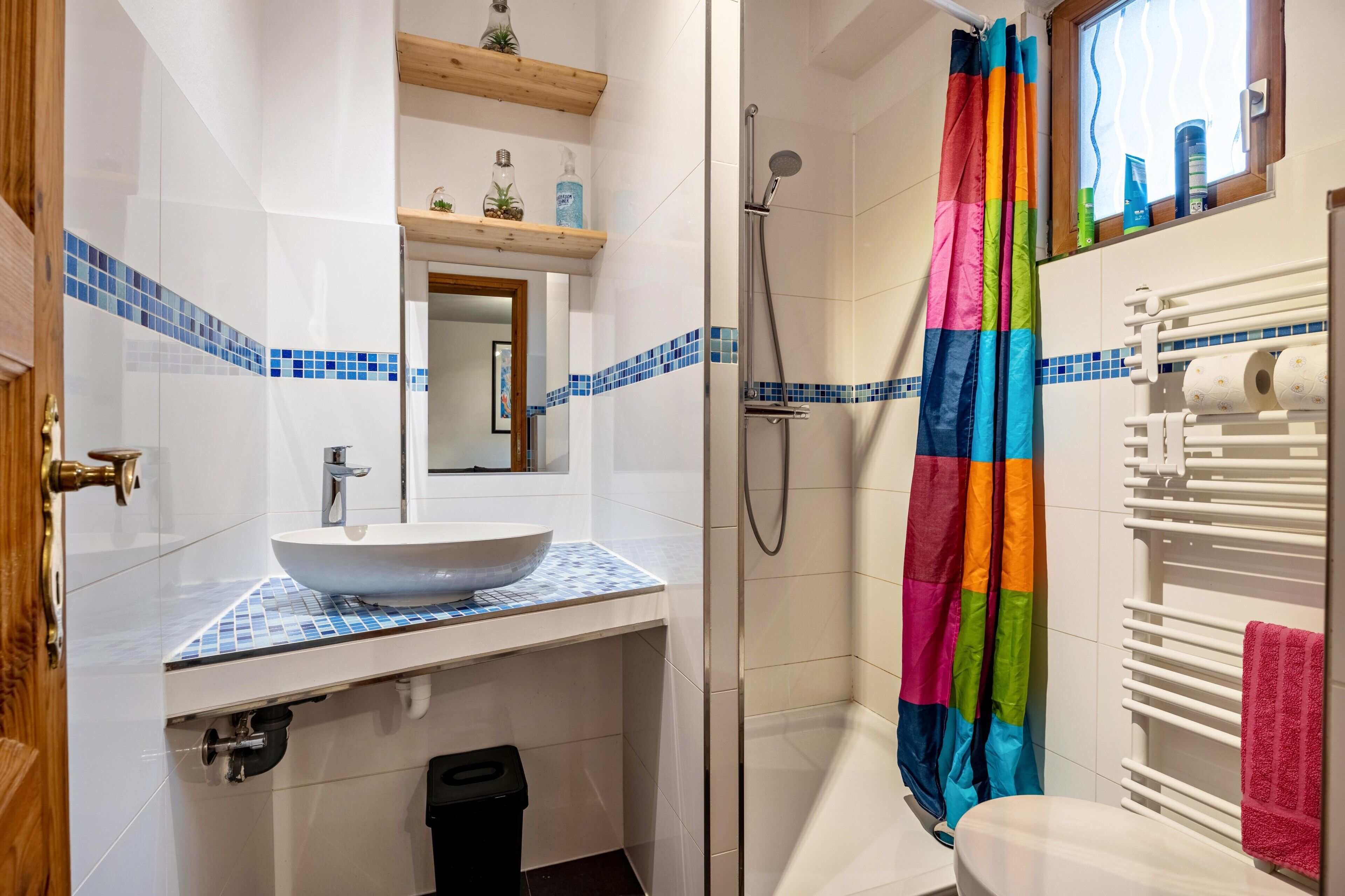 A bathroom with a white sink, a shower with a colorful curtain, and a towel rack.