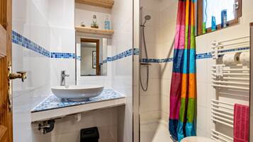 A bathroom with a white sink, a shower with a colorful curtain, and a towel rack.