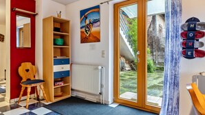 A room with a checkered floor, a wooden chair, a bookshelf, a radiator, a painting, a door leading outside, and a 'HOME' sign. - Apartment 'Einzimmer Appartment' with Private Terrace and Wi-Fi (Bad Gandersheim)