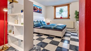 A bedroom with a bed, a window, a radiator, and a checkered floor. - Apartment 'Einzimmer Appartment' with Private Terrace and Wi-Fi (Bad Gandersheim)