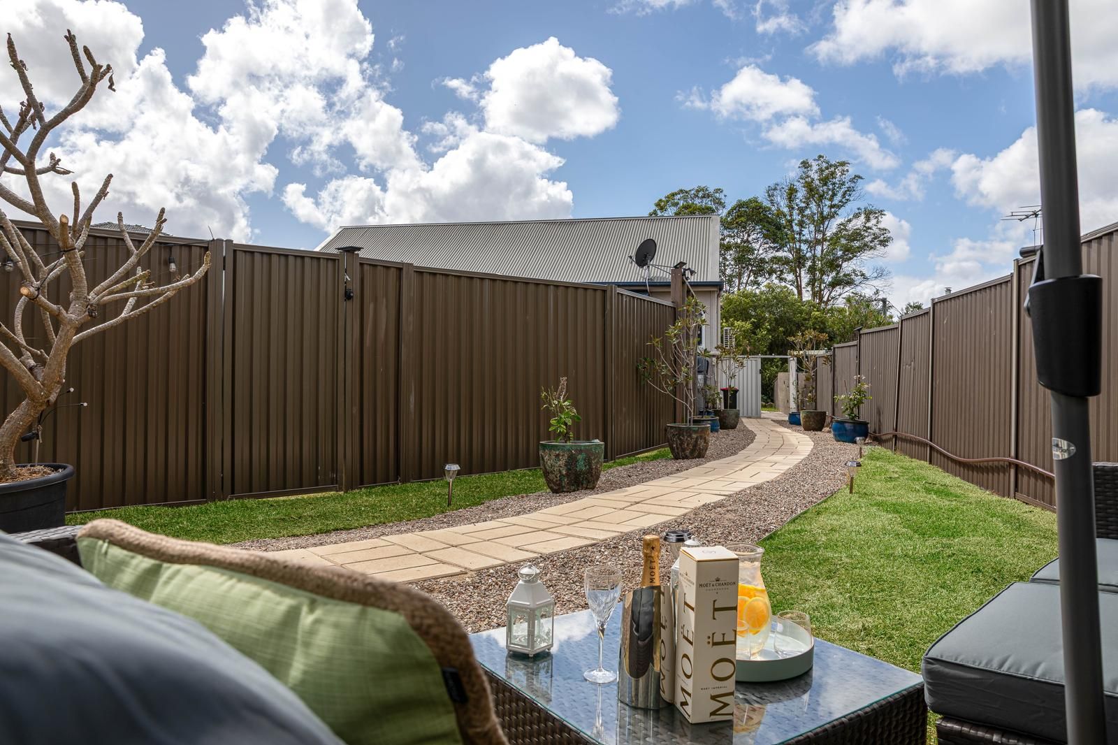 Un patio trasero con terraza, cerca y mobiliario exterior.