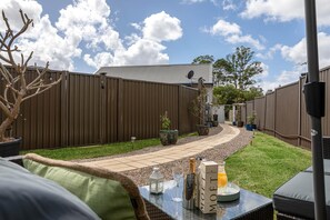 A backyard with a patio, a fence, and outdoor furniture.