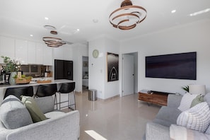 A modern living room with grey sofas, a large flat-screen TV, and a minimalist design.
