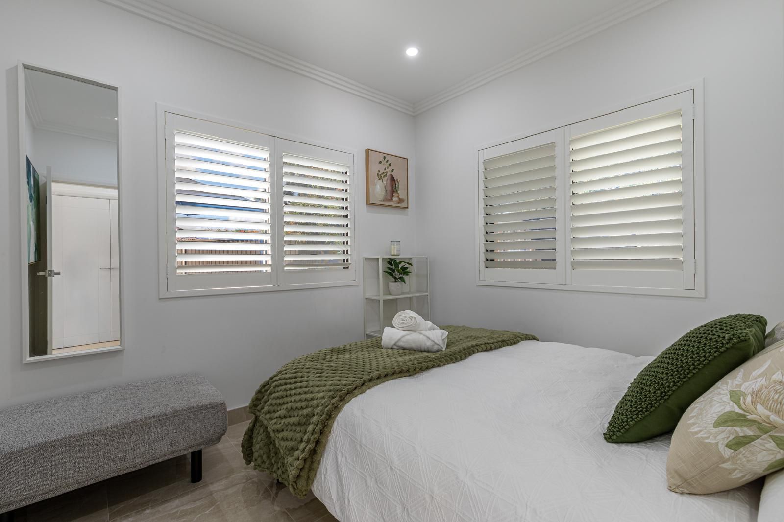 Un dormitorio con una cama, un banco, un estante con toallas y un cuadro en la pared.