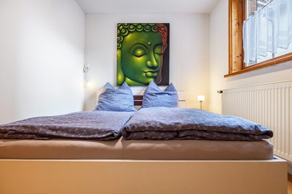 A bed with a headboard, pillows, and a wall-mounted artwork.
