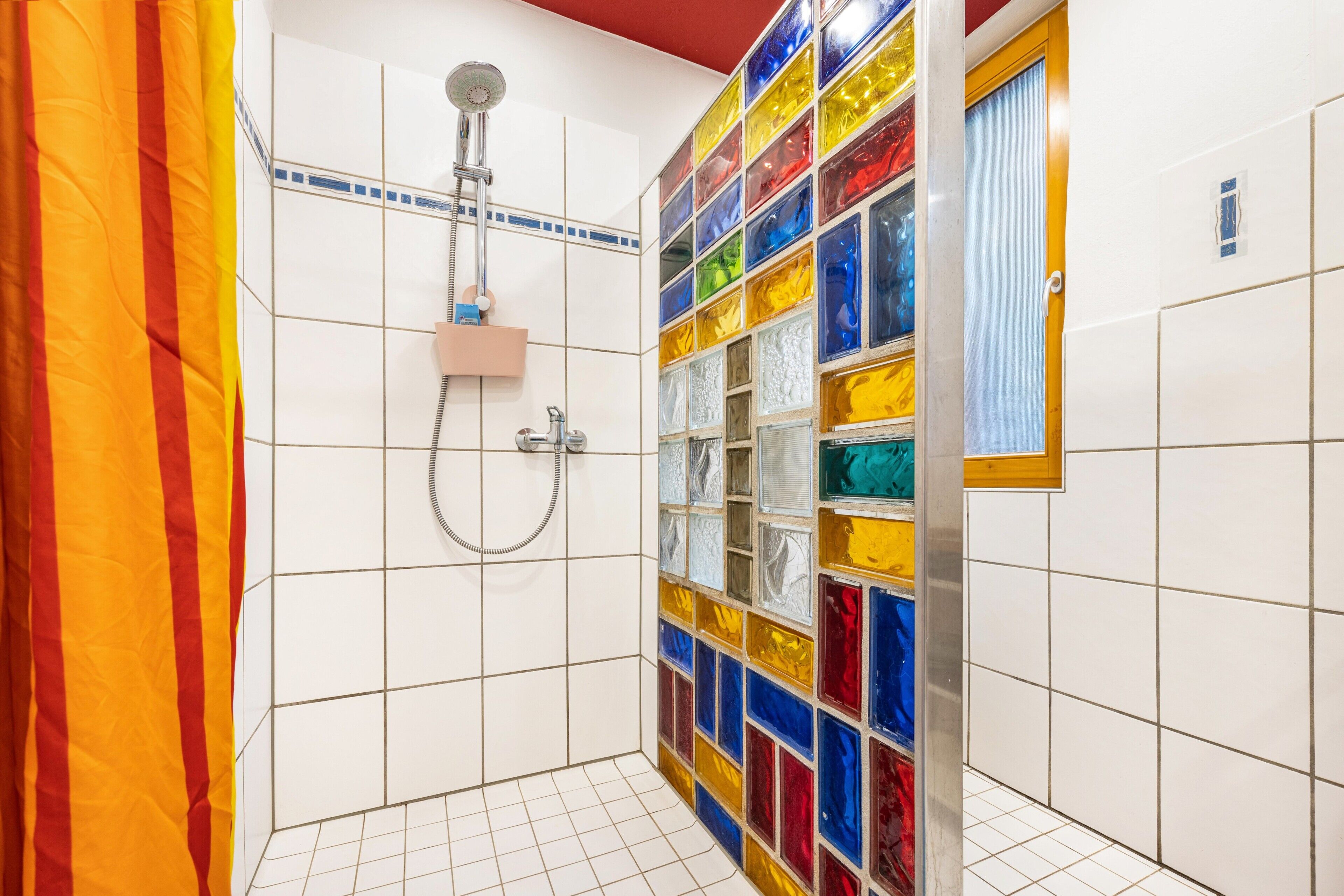 Une salle de bain avec une douche, des murs carrelés et une mosaïque aux couleurs vives.