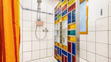 Une salle de bain avec une douche, des murs carrelés et une mosaïque aux couleurs vives.
