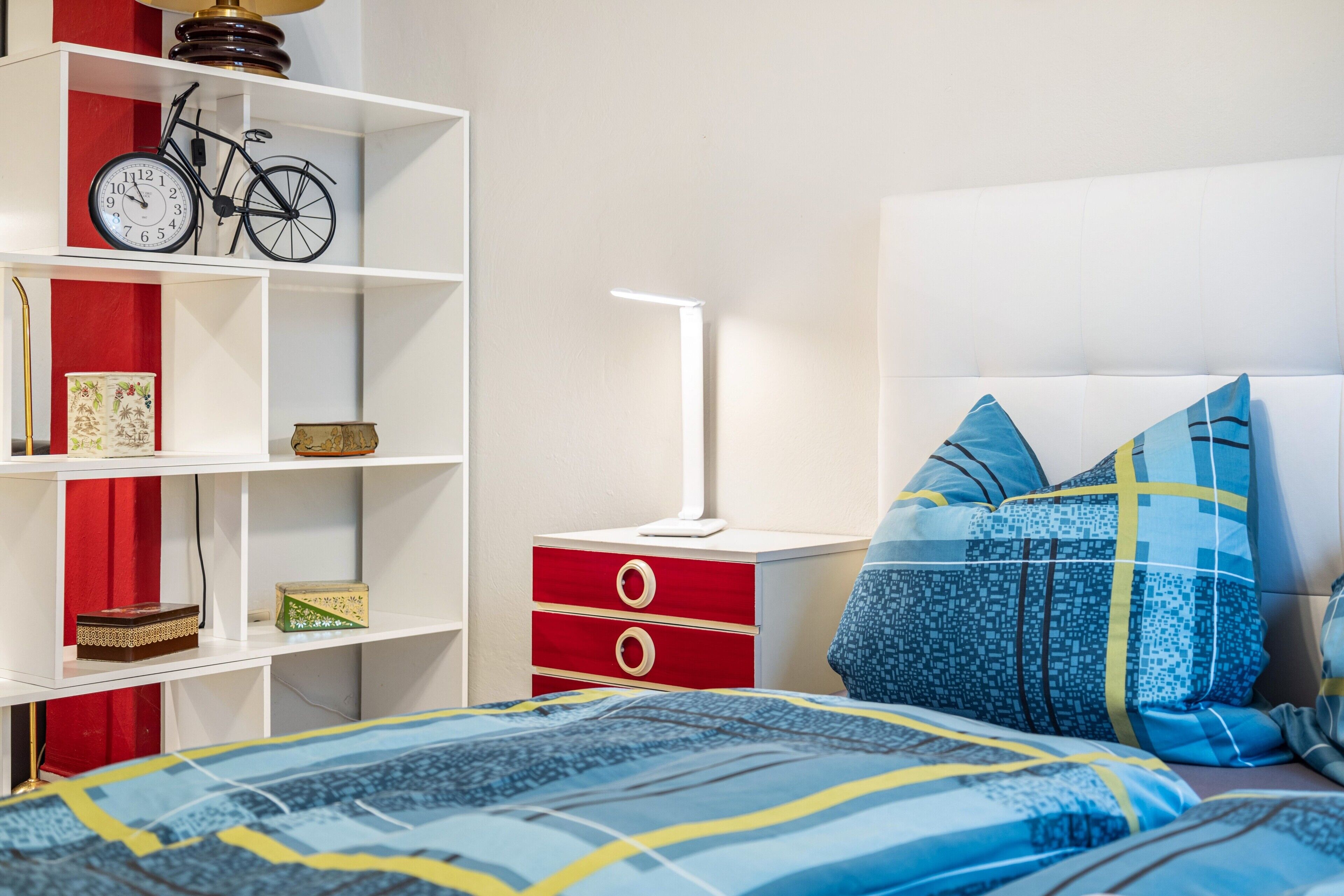 Une chambre à coucher avec un lit, une table de chevet, une lampe, une bibliothèque et une décoration sur le thème du vélo.