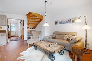 A living room with a sofa, a coffee table, a lamp, and a rustic ceiling.