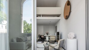 A modern living room with a sofa, coffee table, and chairs. There is a dining area with a table and chairs. A large mirror hangs on the wall. - Future Space in the heart of Darlinghurst (Darlinghurst)