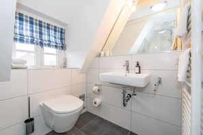 Moderni kylpyhuone, jossa on wc, pesuallas ja pyyheteline.