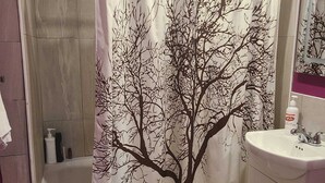 Une salle de bain équipée d’un rideau de douche orné d’un motif d’arbre, d’une baignoire, d’un lavabo et de toilettes.