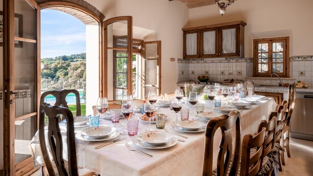 Un comedor con una mesa lista para comer, sillas de madera y vistas al exterior.