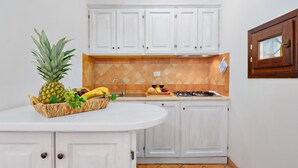 A kitchen with white cabinets, a wooden countertop, a stove, and a fruit basket.