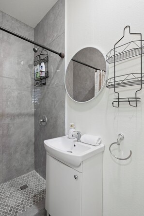 A modern bathroom with a shower, a sink, and a mirror.