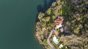 Vista aérea de uma propriedade com piscina, um gazebo e uma casa grande com telhado de telhas.