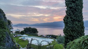 Área de piscina com espreguiçadeiras e vista para um lago e montanhas.