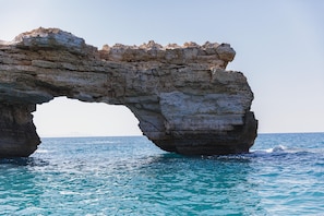 A natural rock arch formation in a body of water. - Villa Red Sunset by Estia (Rethymno)