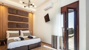 A modern hotel room with a large bed, a flat-screen TV, an air conditioning unit, and a sliding glass door to the outside.