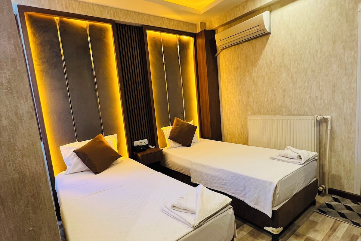 Habitación de hotel con dos camas, diseño moderno y aire acondicionado integrado.