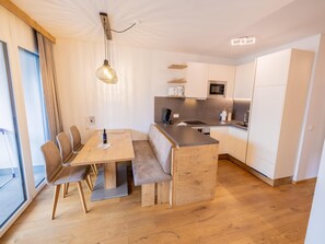 A modern kitchen with a wooden dining table, bench seating, and a built-in island.