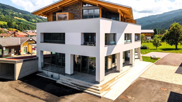 Un edificio moderno de dos pisos con amplios ventanales y un nivel superior de madera.