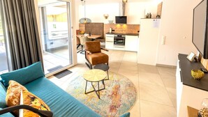 Una sala de estar moderna con sofá, una mesita redonda y una zona de cocina con mesa y sillas para comer.
