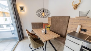 Una cocina moderna con una mesa de madera, dos sillas acolchadas, una lámpara colgante y una decoración de cabeza de toro en la pared.