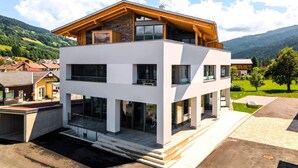 Un edificio moderno de dos plantas con techo plano, ventanas amplias y un piso superior de madera.